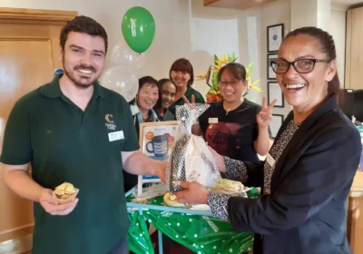 Sam Reid, Home Manager of The Aldbury, presents the Golden Cup Cake prize to winner and Housekeeping colleague Michael Sheppard. With them are, from second left: colleagues Merle Foster, Kanya Brannon, Janette Burgess and Nimpha Salmon