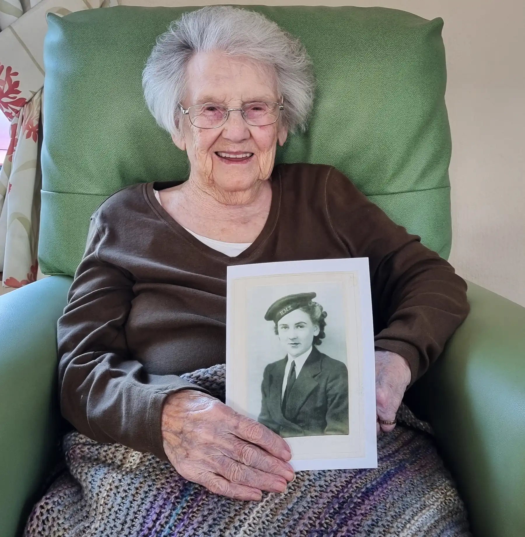 Elizabeth House resident Kathleen with a photo of herself aged 18 in her Wren uniform