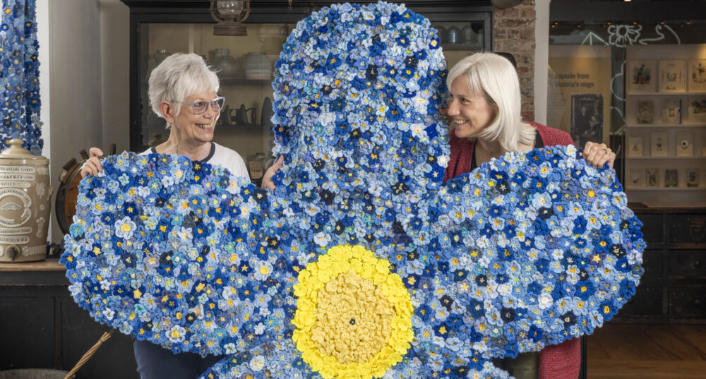 Museum of East Dorset staff, Heather Bird and Amanda Peroni with a giant forget-me-not flower which is made from thousands of tiny donated knitted flowers Picture: ZacharyCulpin/Bournemouth News and Picture Service