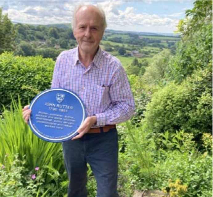 Sir John Stuttard holding the John Rutter Blue Plaque